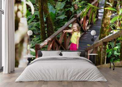 Child looking at flower in jungle. Wall mural