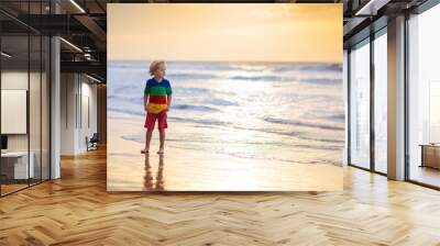 Child playing on ocean beach. Kid at sunset sea. Wall mural