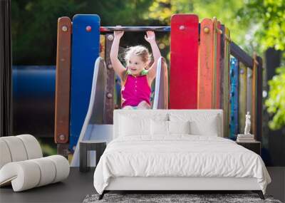 Child playing on outdoor playground in summer Wall mural