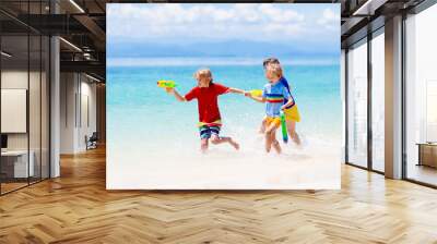 Child with toy water gun. Kids vacation beach fun. Wall mural