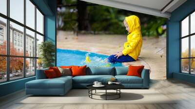 Kid in swimming pool in rain. Tropical storm. Wall mural