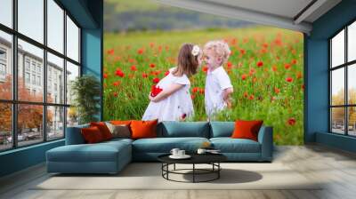 Kids playing in red poppy flower field Wall mural