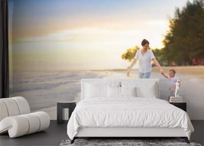 Mother and baby on tropical beach at sunset. Wall mural