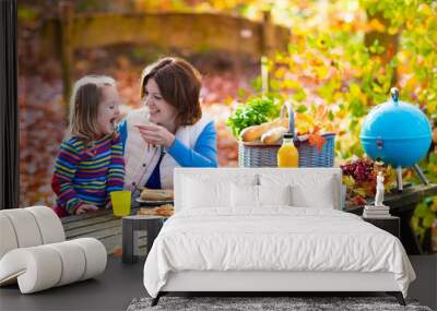 Mother and daughter set table for picnic in autumn Wall mural