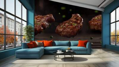 Three grilled lamb chops, sprinkled with herbs,  floating against a dark background and a wooden table. Wall mural