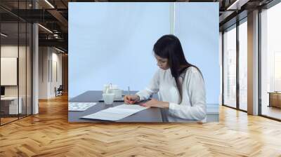 Young woman signing formal documents sitting at the cafe table Wall mural