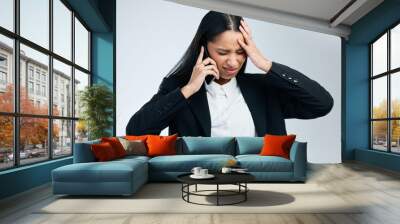 Business woman, phone call and stress headache for difficult client, burnout and frustrated in studio. Lady, migraine pain and mobile chat with worry, mistake and work crisis by gray background Wall mural