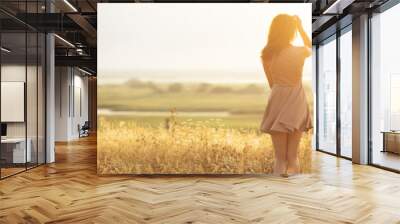 dreamy girl in a field at sunset, a young woman in a haze from the sun enjoying nature, romantic style Wall mural