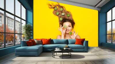 fashion portrait of beautiful girl lying on colored background with kiwi fruit slices on long hair, people and food, young peaceful woman takes care of beauty and body Wall mural