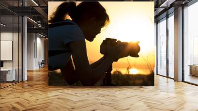 silhouette portrait of a young woman photographing a beautiful nature at sunset on photo equipment Wall mural