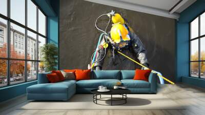 An industrial diver with scuba diving and in a protective suit climbs out of the water along the stairs. Wall mural