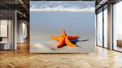 Orange starfish on a sandy beach with blue ocean waves in the background Wall mural