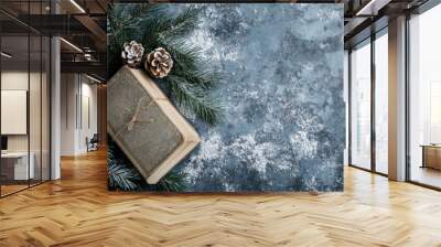 Christmas background with an old book, pine branches, and snow on a grunge blue stone table. Flat lay style, top view. Wall mural