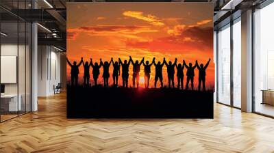 Silhouette group of happy friends is having fun with raised hands against sunset mountains Wall mural