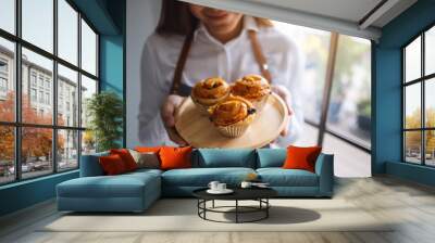 A waitress holding a wooden plate of raisin danish Wall mural