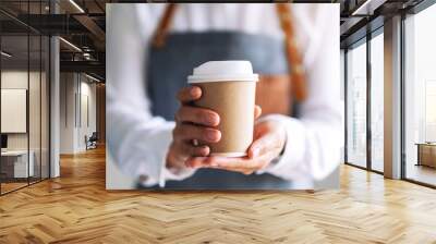 A waitress holding and serving a paper cup of hot coffee in cafe Wall mural