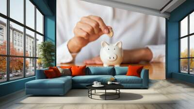 A woman putting coins into piggy bank for saving money concept Wall mural