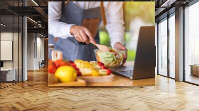 A woman videoblogger cooking in the kitchen and filming, online learning cooking class concept Wall mural