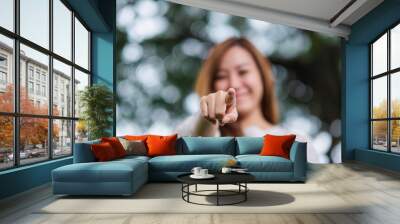 Blurred image of a beautiful young asian woman pointing finger to the camera in the park Wall mural