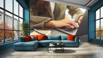 Businesswoman using and typing on laptop computer with paperwork on the table in office Wall mural