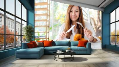 Closeup image of a beautiful asian woman using knife and fork to eat fried chicken in restaurant Wall mural