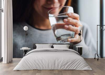 Closeup image of a beautiful young asian woman holding a glass of water to drink Wall mural