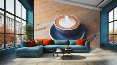 Closeup image of a blue cup of hot latte coffee with latte art on vintage wooden table in cafe Wall mural