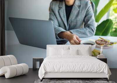 Closeup image of a business woman using and working on laptop computer while drinking coffee in office Wall mural