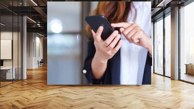 Closeup image of a businesswoman holding and using mobile phone Wall mural