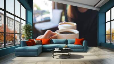 Closeup image of a couple people clinking coffee cups together in cafe Wall mural