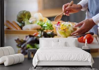 Closeup image of a female chef cooking and holding a bowl of fresh mixed vegetables salad in kitchen Wall mural