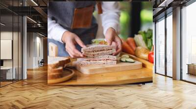 Closeup image of a female chef cooking and holding a piece of whole wheat ham cheese sandwich in kitchen Wall mural