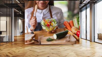 Closeup image of a female chef cooking fresh mixed vegetables salad in kitchen Wall mural