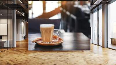 Closeup image of a glass of hot coffee on wooden table in cafe Wall mural