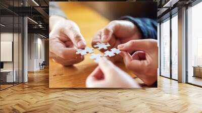 Closeup image of a group of people holding and putting a piece of white jigsaw puzzle together Wall mural