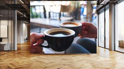 Closeup image of a man and a woman clinking white coffee mugs in cafe Wall mural