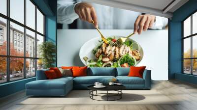 Closeup image of a woman eating chicken salad on table in the restaurant Wall mural