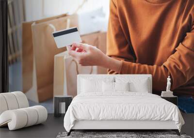 Closeup image of a woman holding credit card with shopping bags at home for online shopping concept Wall mural