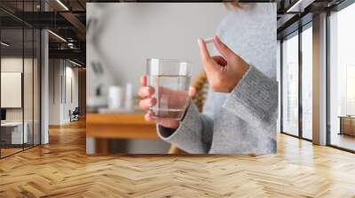 Closeup image of a woman holding white pills and a glass of water Wall mural