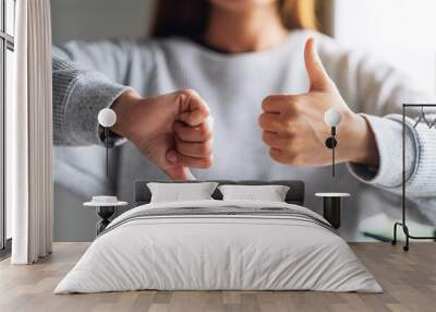 Closeup image of a woman making thumbs up and thumbs down hands sign Wall mural