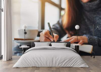 Closeup image of a woman writing on a blank notebook on the table Wall mural