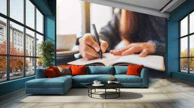 Closeup image of a woman writing on a blank notebook on the table Wall mural