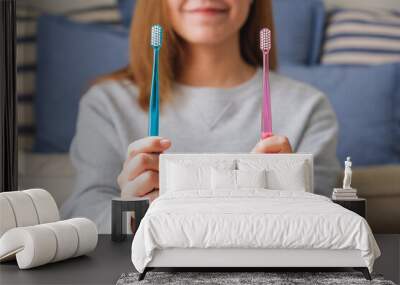 Closeup image of a young woman holding and showing two toothbrush Wall mural