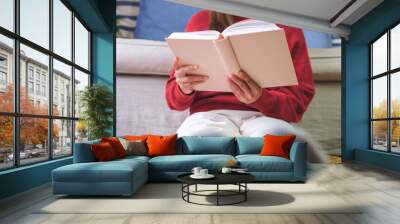 Closeup image of a young woman reading a book at home Wall mural