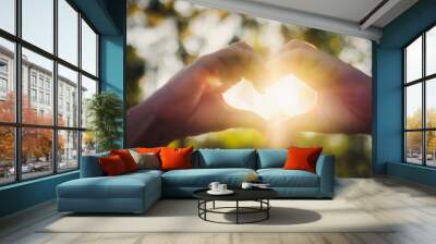 Closeup image of sunlight shining through heart hands sign with nature background Wall mural