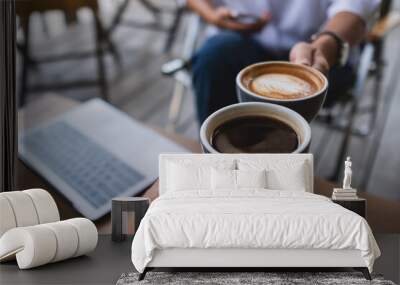 Closeup image of two businessman clinking coffee cups together while working and meeting with laptop computer on the table Wall mural