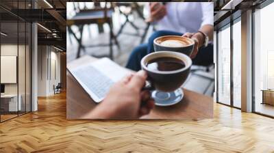 Closeup image of two businessman clinking coffee cups together while working and meeting with laptop computer on the table Wall mural