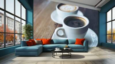 Closeup image of two white cups of hot latte coffee and Americano coffee on vintage wooden table in cafe Wall mural