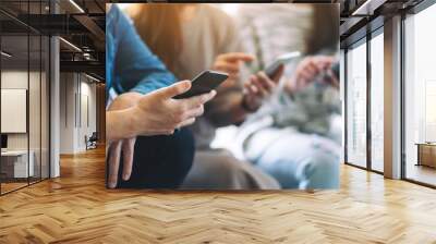 Group of people using and looking at mobile phone and tablet pc while sitting together Wall mural