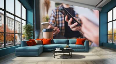 Group of young people holding and using their mobile phones while sitting together Wall mural